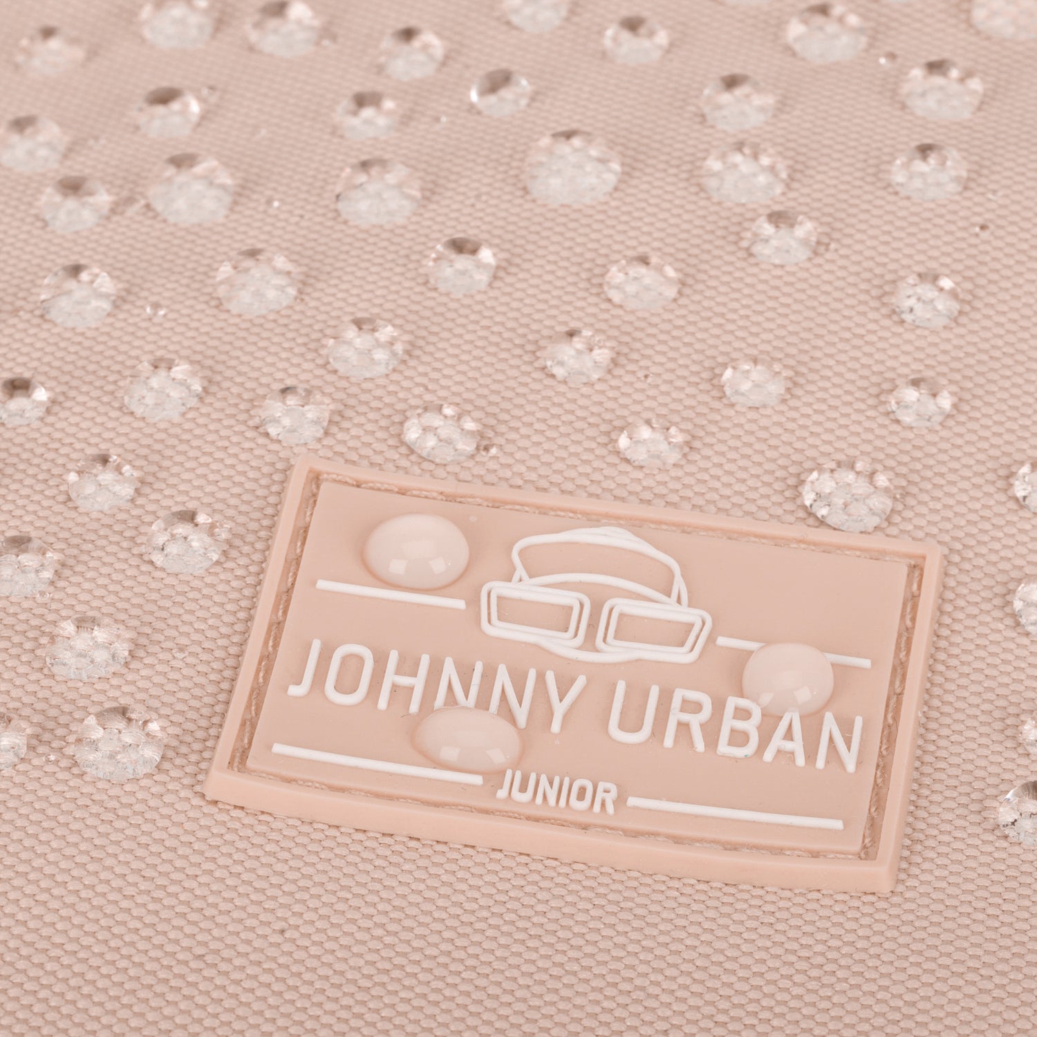 Nahaufnahme des rosa Johnny Urban Junior Labels mit Wassertröpfchen auf wasserdichtem Material