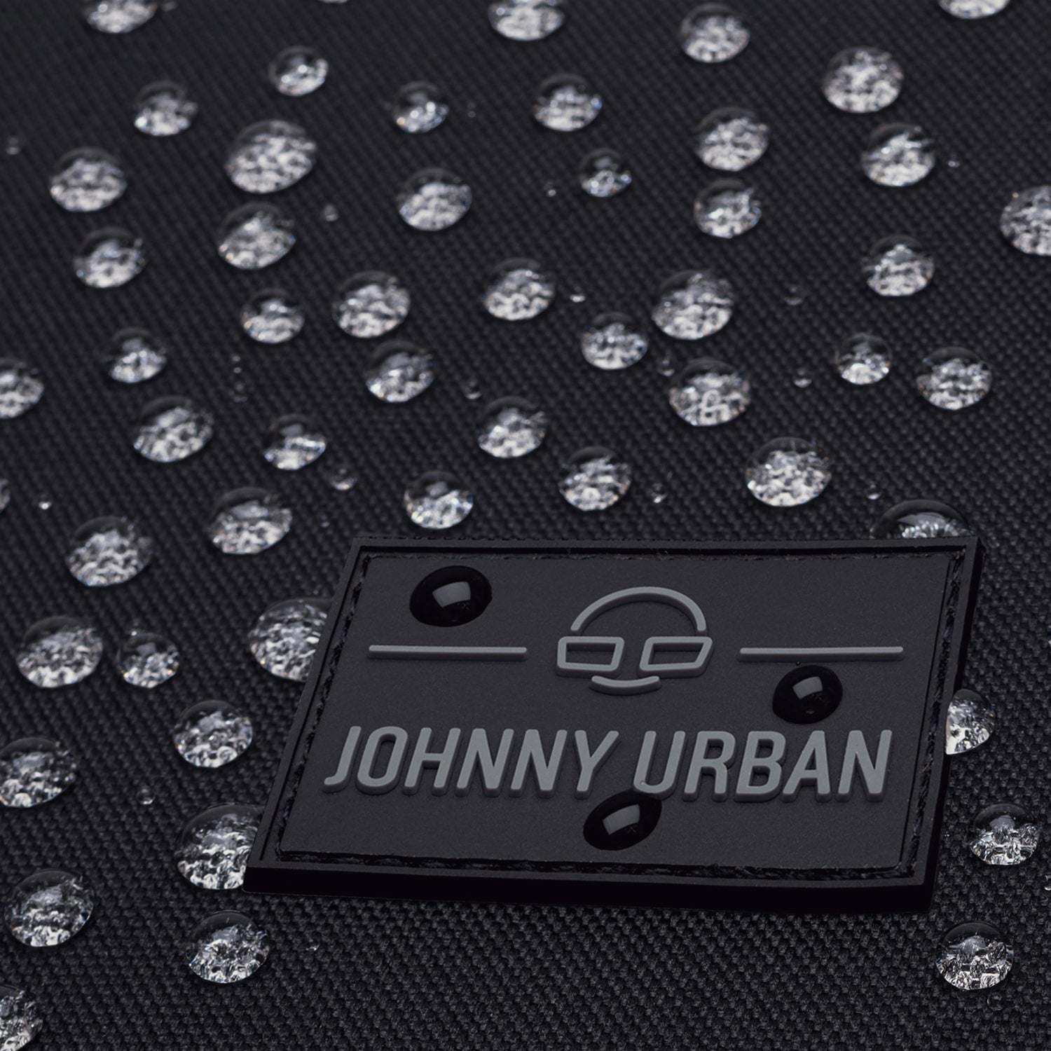 Wasserabweisendes schwarzes Material mit Johnny Urban Logo und Wasserperlen darauf
