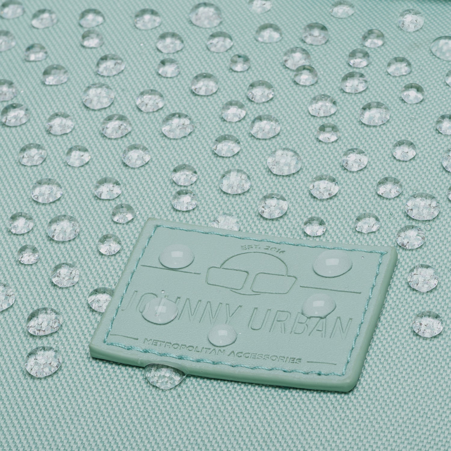Nahaufnahme des mintgrünen Johnny Urban Rolltop-Rucksacks Robin Medium mit Wassertröpfchen auf dem wasserabweisenden Stoff
