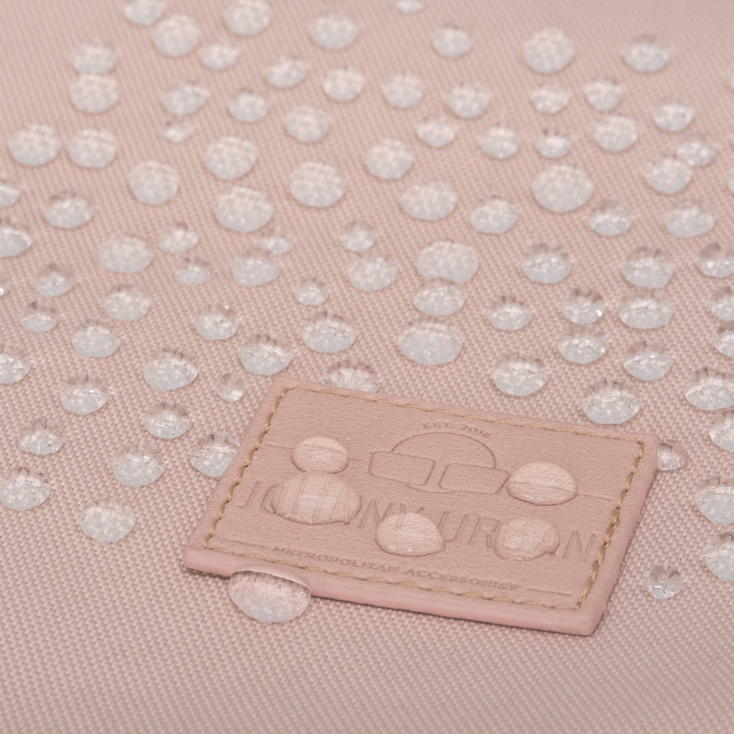 Wasserabweisendes Material des rosa Rolltop Rucksacks 'Robin Medium' von Johnny Urban mit Wassertropfen auf der Oberfläche