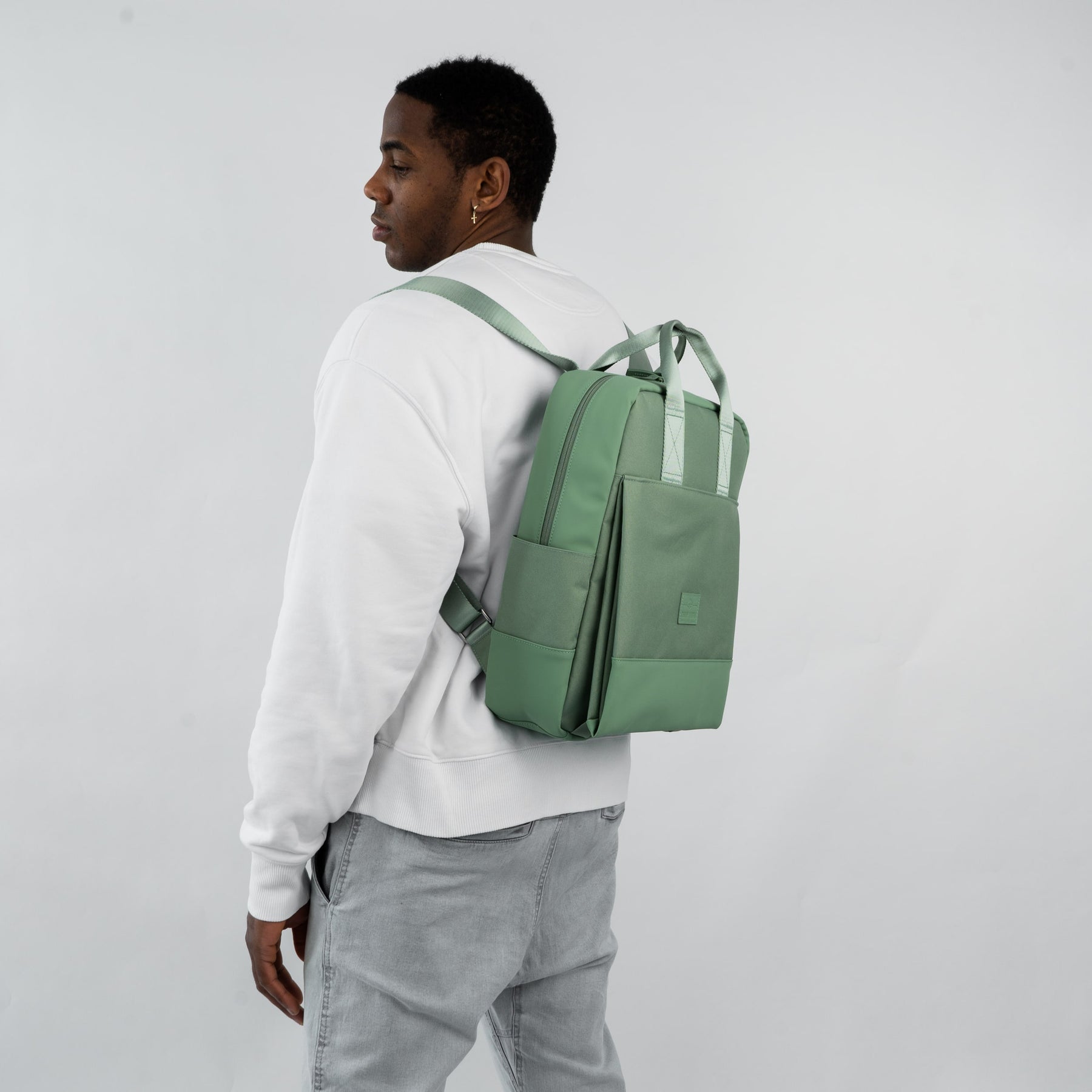 Mann trägt hellgrünen Rucksack 'Jona Large' mit rechteckiger Form und zwei Tragegriffen