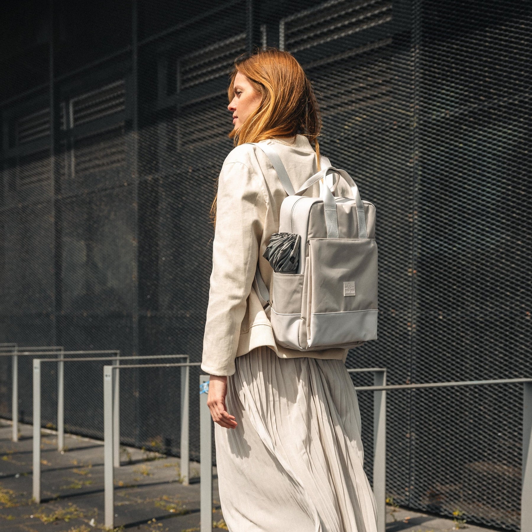 Frau mit beigefarbenem Rucksack 'Jona Large' von Johnny Urban, seitlich am Körper getragen