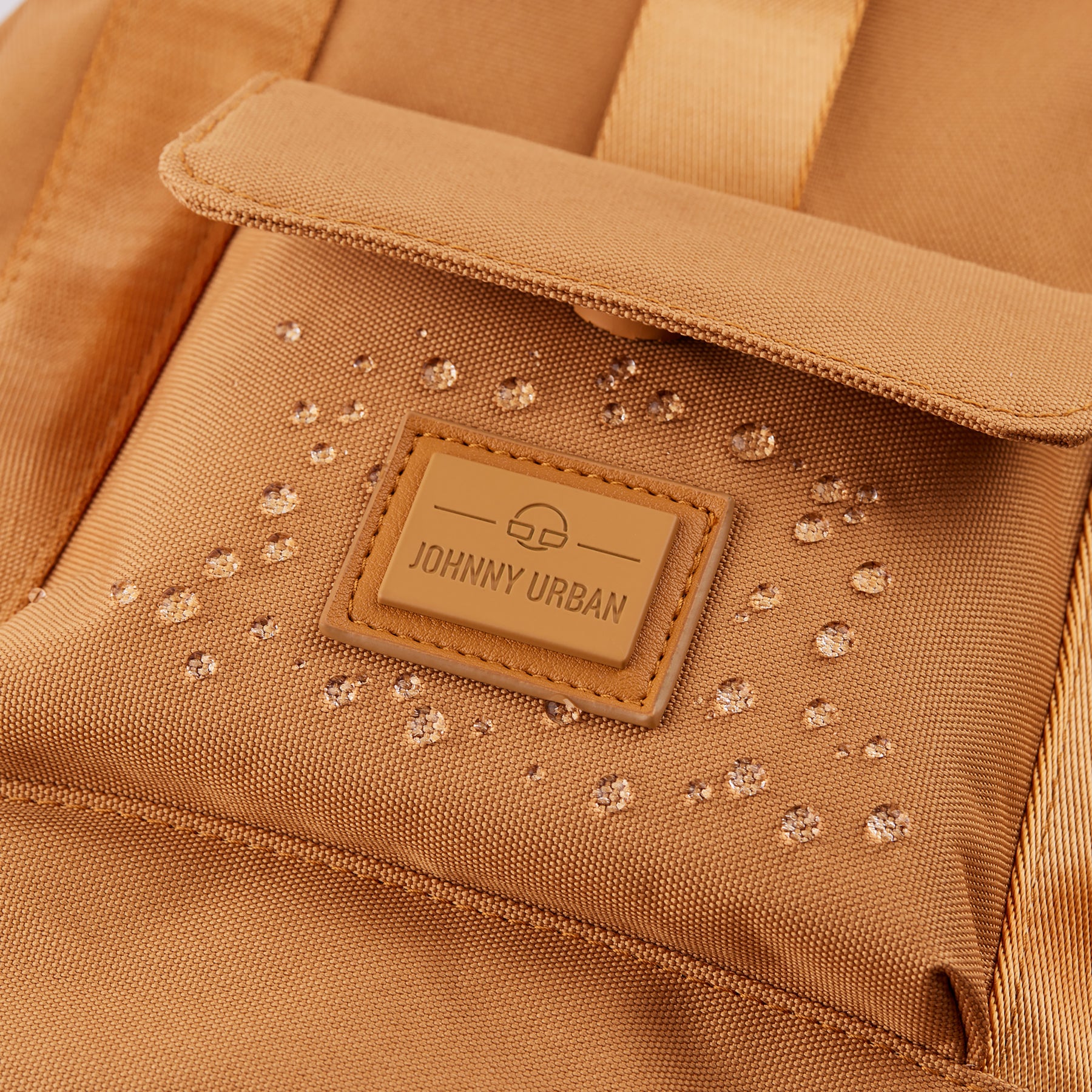 Nahaufnahme des wasserabweisenden caramel-braunen Rucksacks 'Jules' von Johnny Urban mit Wassertropfen auf der Oberfläche