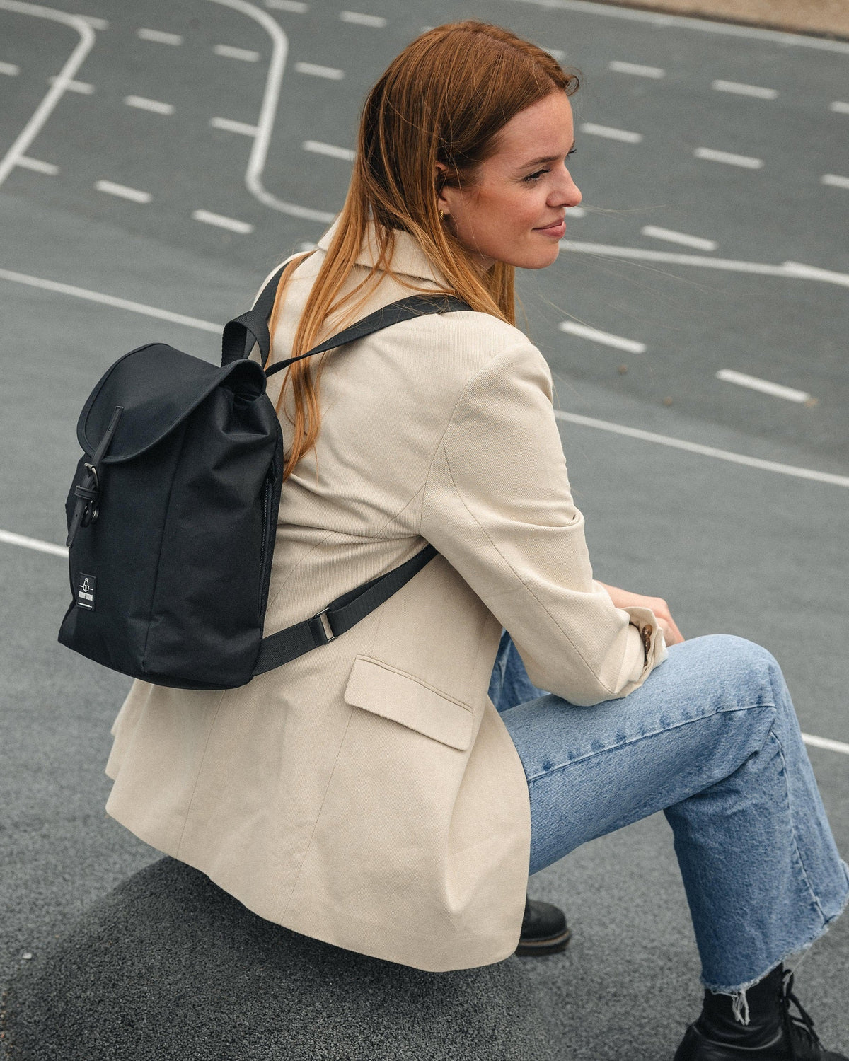 Frau sitzt auf Straße mit kleinem schwarzen Rucksack Damen 'Romy' von Johnny Urban