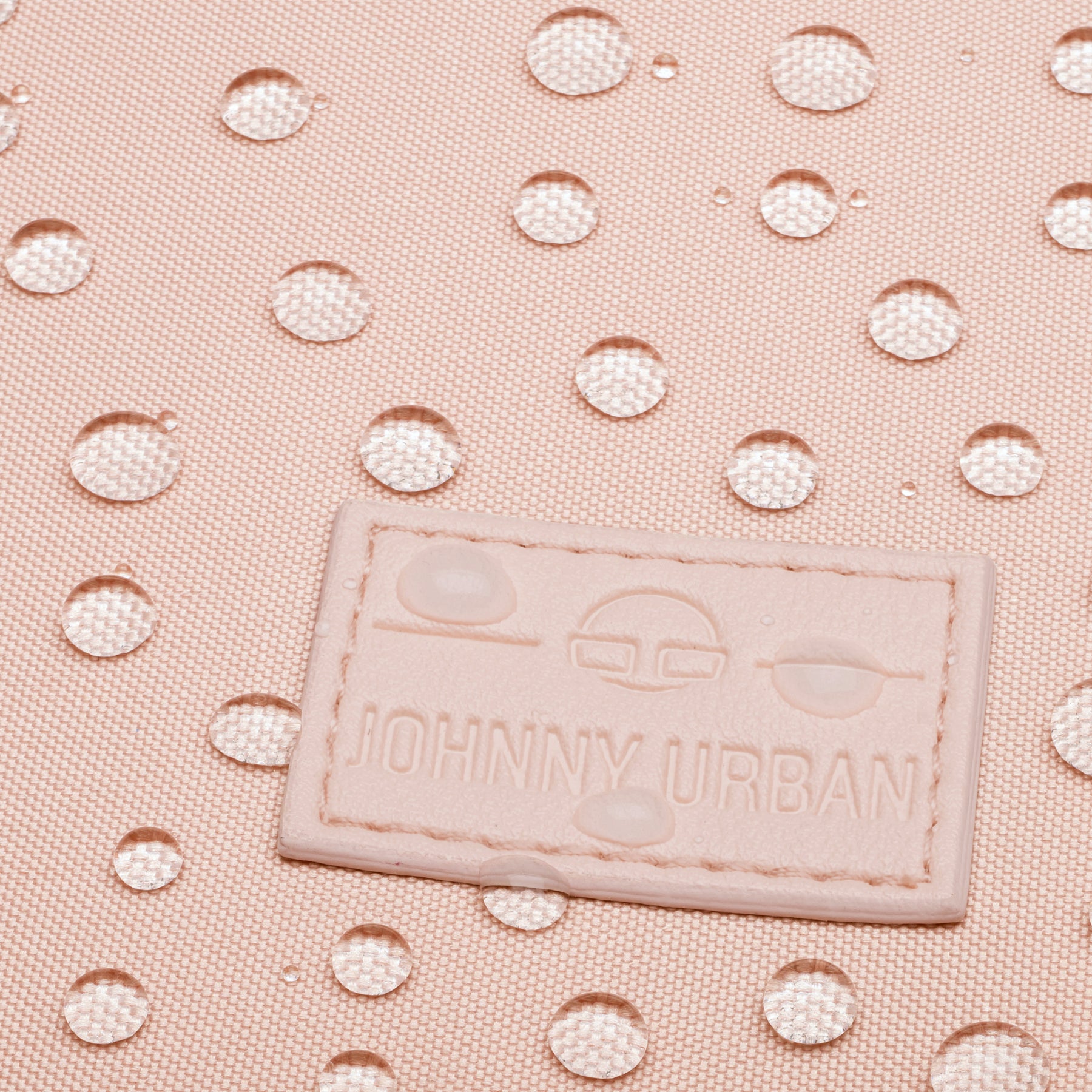 Nahaufnahme eines wasserabweisenden, rosa Stoffes mit Johnny Urban Logo-Patch