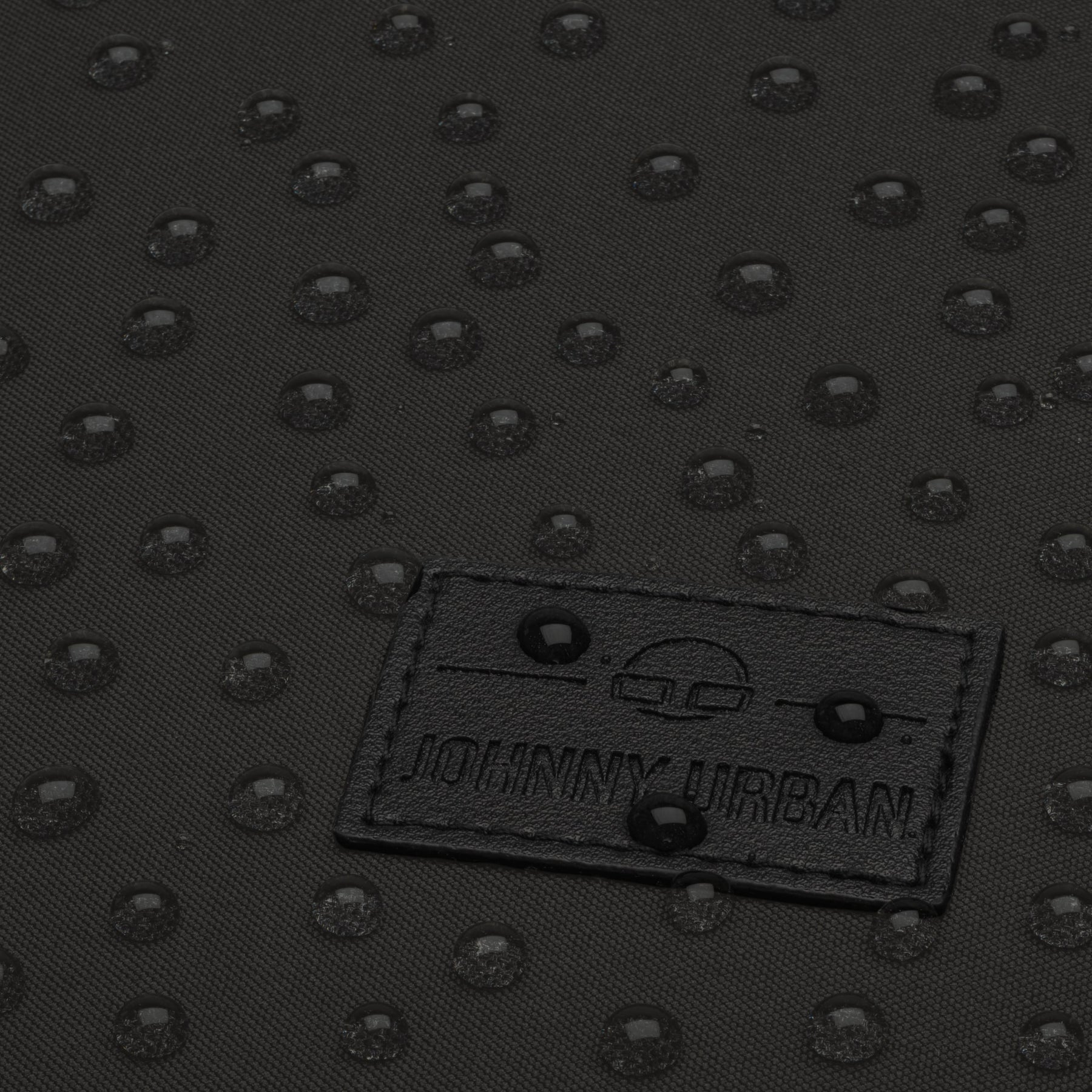 Nahaufnahme des wasserabweisenden schwarzen Stoffes des Rucksacks 'Jona Medium' mit sichtbaren Wassertropfen