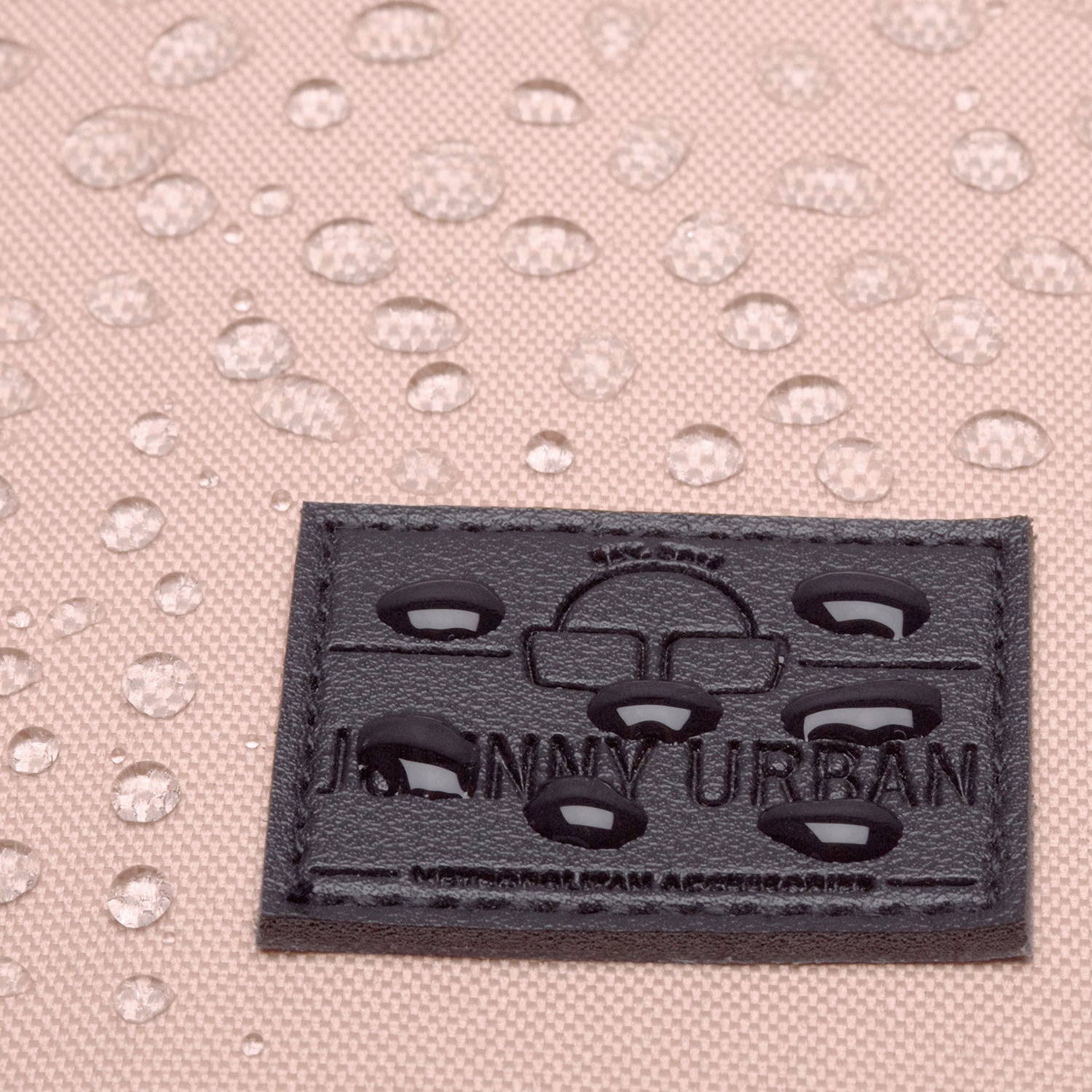 Nahaufnahme des schwarzen Johnny Urban Logos auf einem rosa wasserfesten Rucksack mit Wassertröpfchen