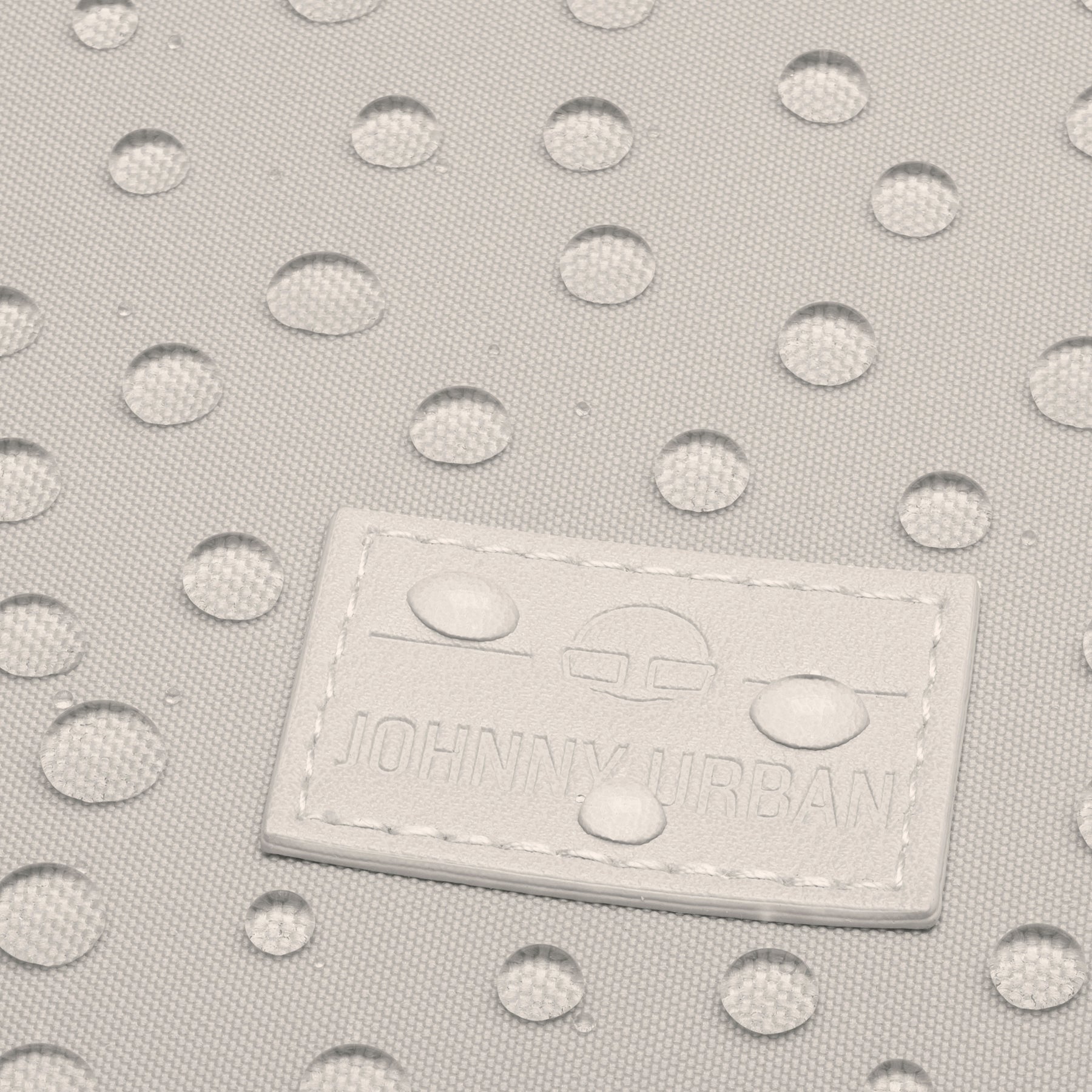 Wasserabweisender beiger Stoff des "Jona Small" Rucksacks mit Johnny Urban Logo-Patch und Wassertropfen