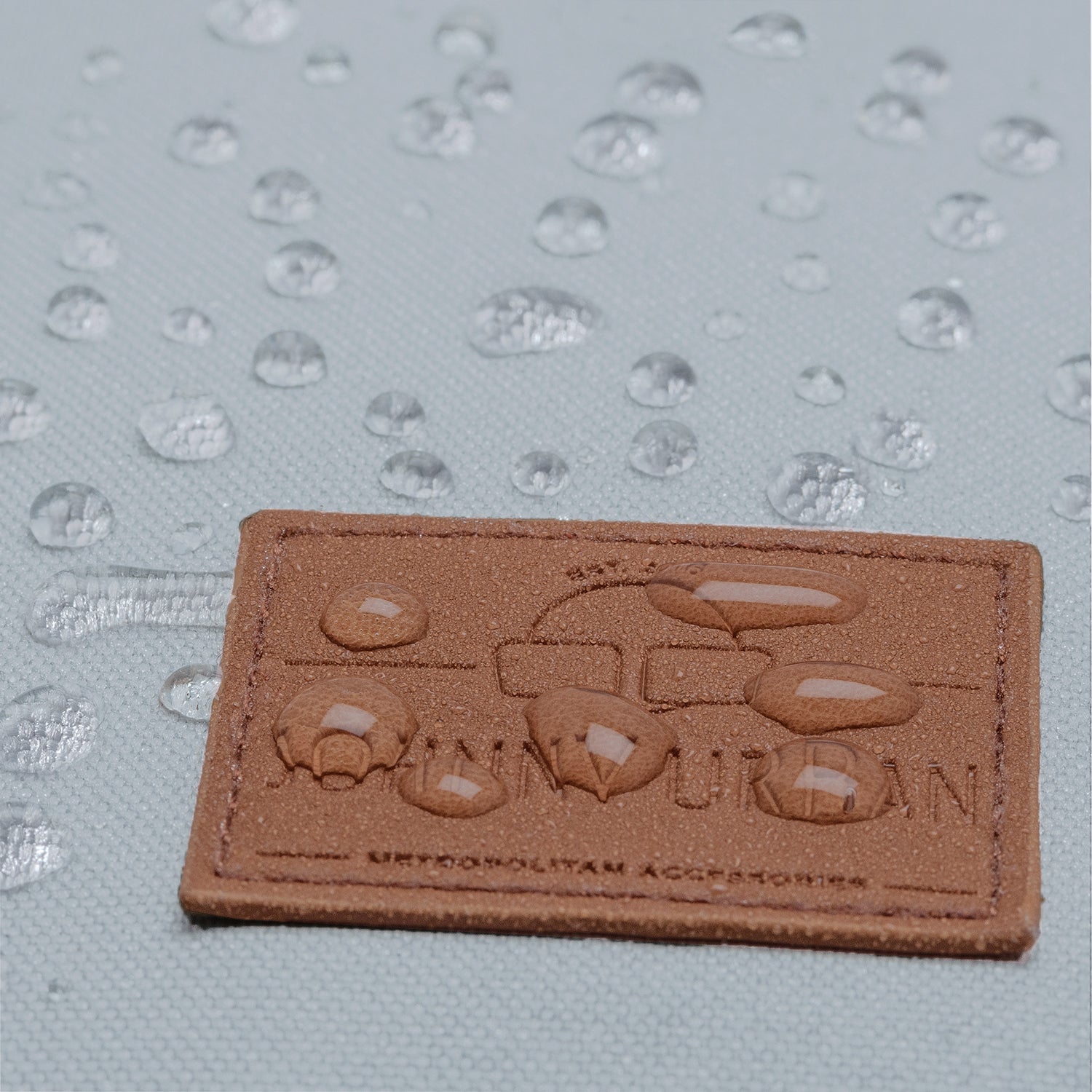 Wasserabweisendes Material mit Johnny Urban Logo auf einem braunen Lederetikett des Rucksacks 'Liam'