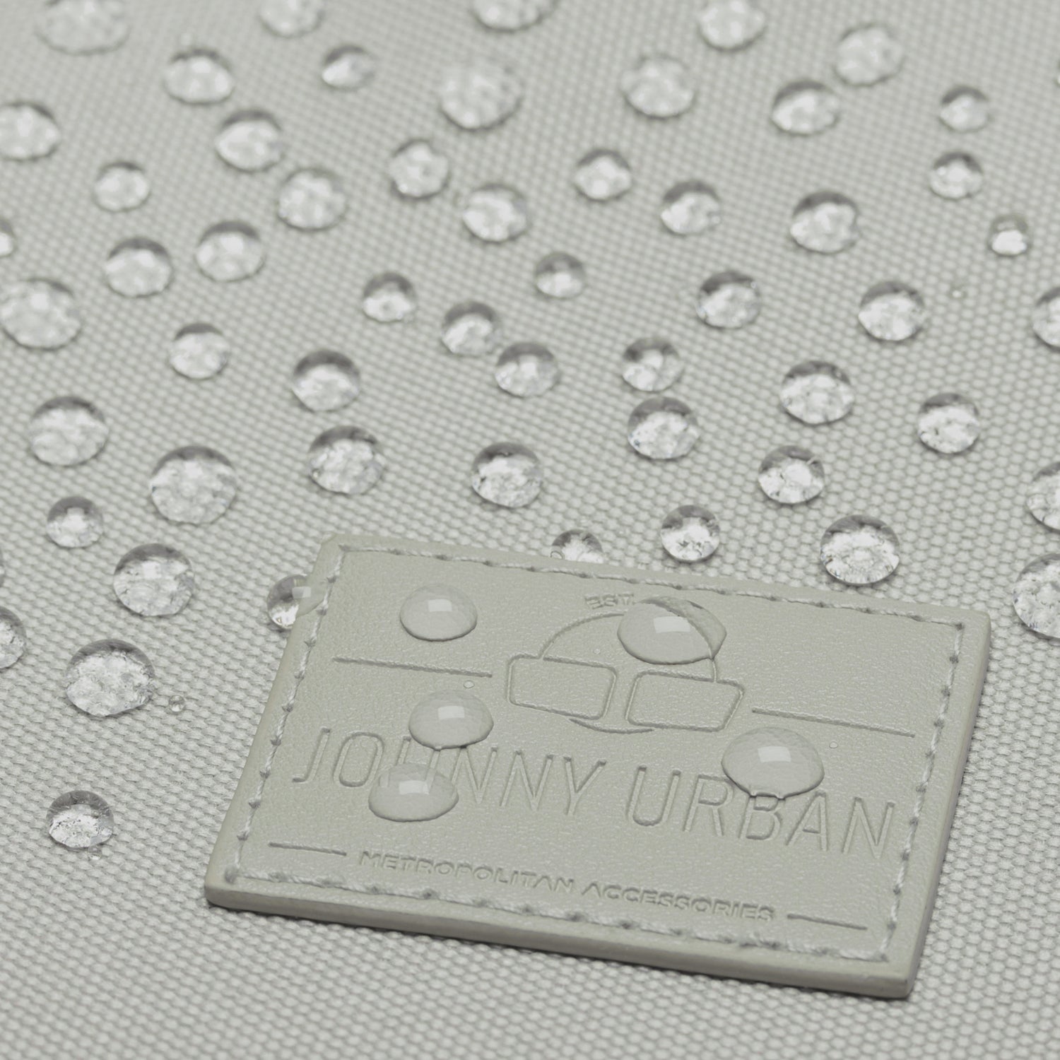 Wassertropfen auf grauem Stoff mit 'Johnny Urban' Logoetikett vom Rucksack 'Milo'