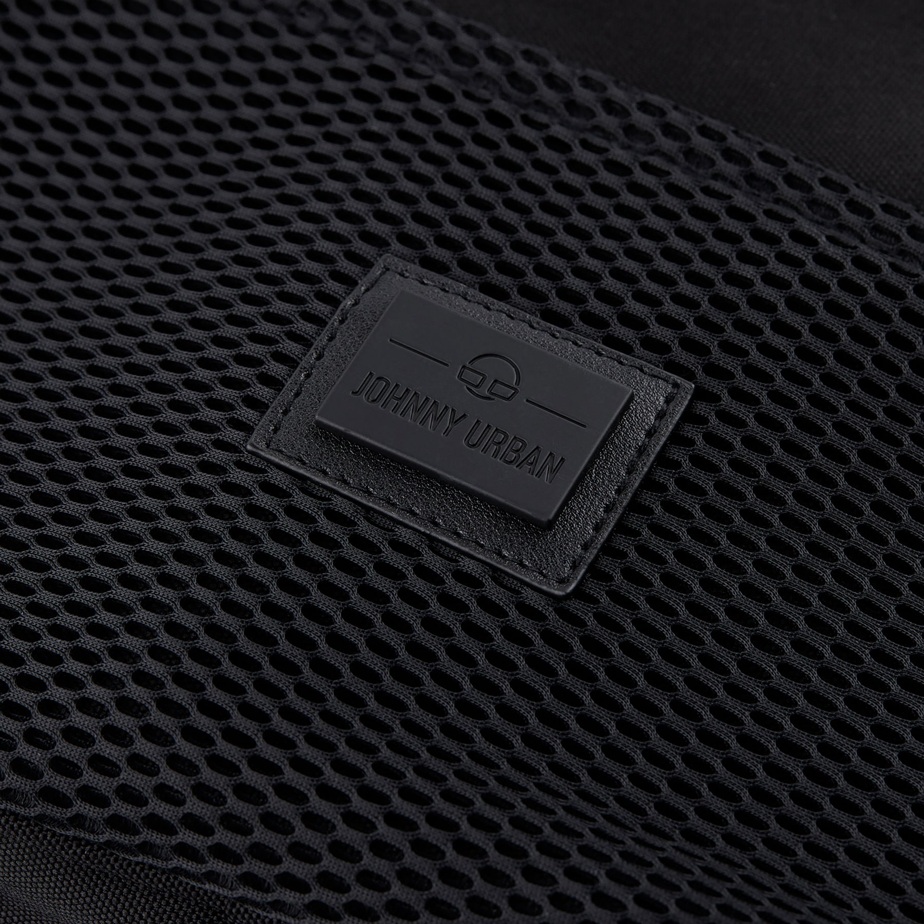 Nahaufnahme des schwarzen Johnny Urban Logos auf einem schwarzen Netzstoff
