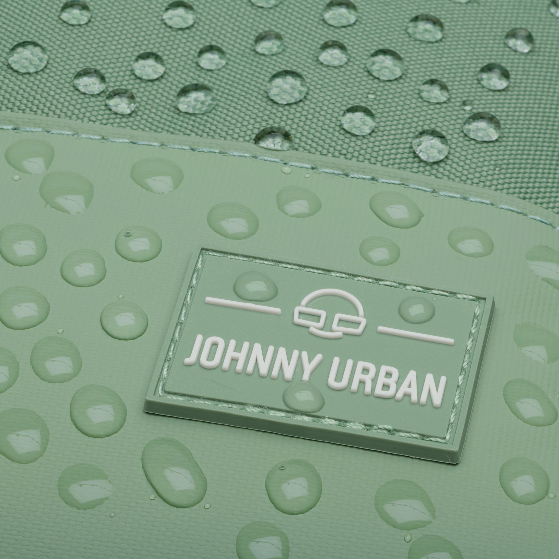 Nahaufnahme des Johnny Urban Logos auf dem wasserdichten Rucksack 'Mika' mit Wassertröpfchen