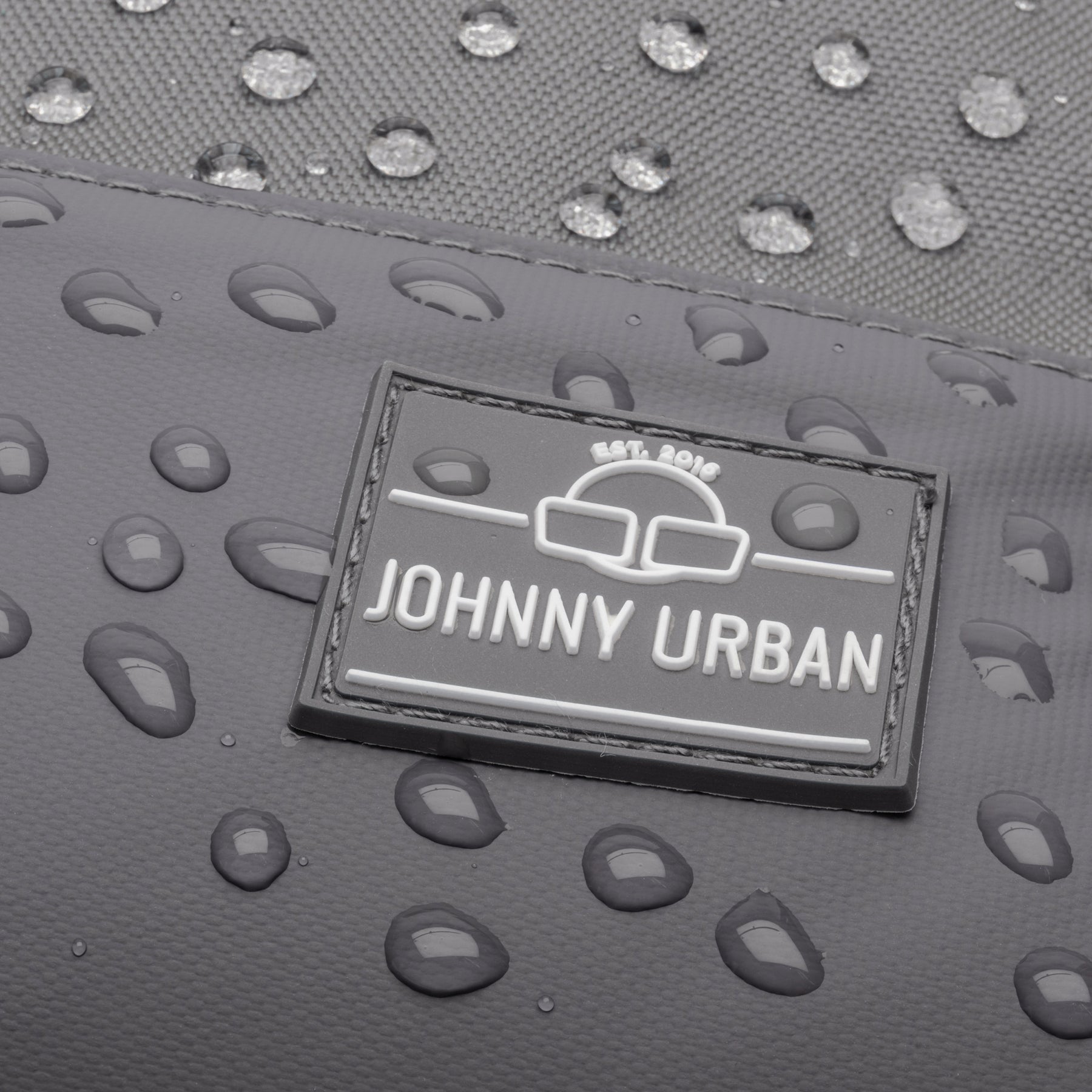 Nahaufnahme des wasserdichten dunkelgrauen Johnny Urban Rucksacks 'Mika' mit Wassertropfen auf der Oberfläche