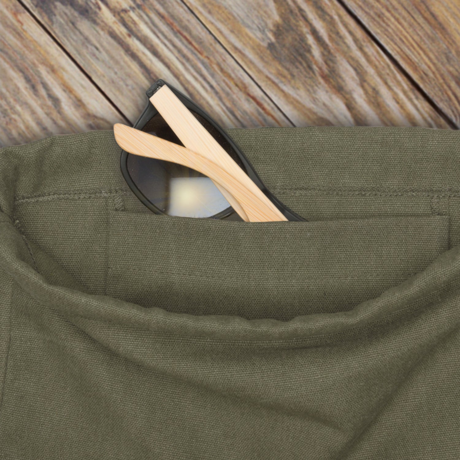 Grüner Turnbeutel 'Luke' mit Außentasche, in der eine Sonnenbrille mit Holzbügeln steckt