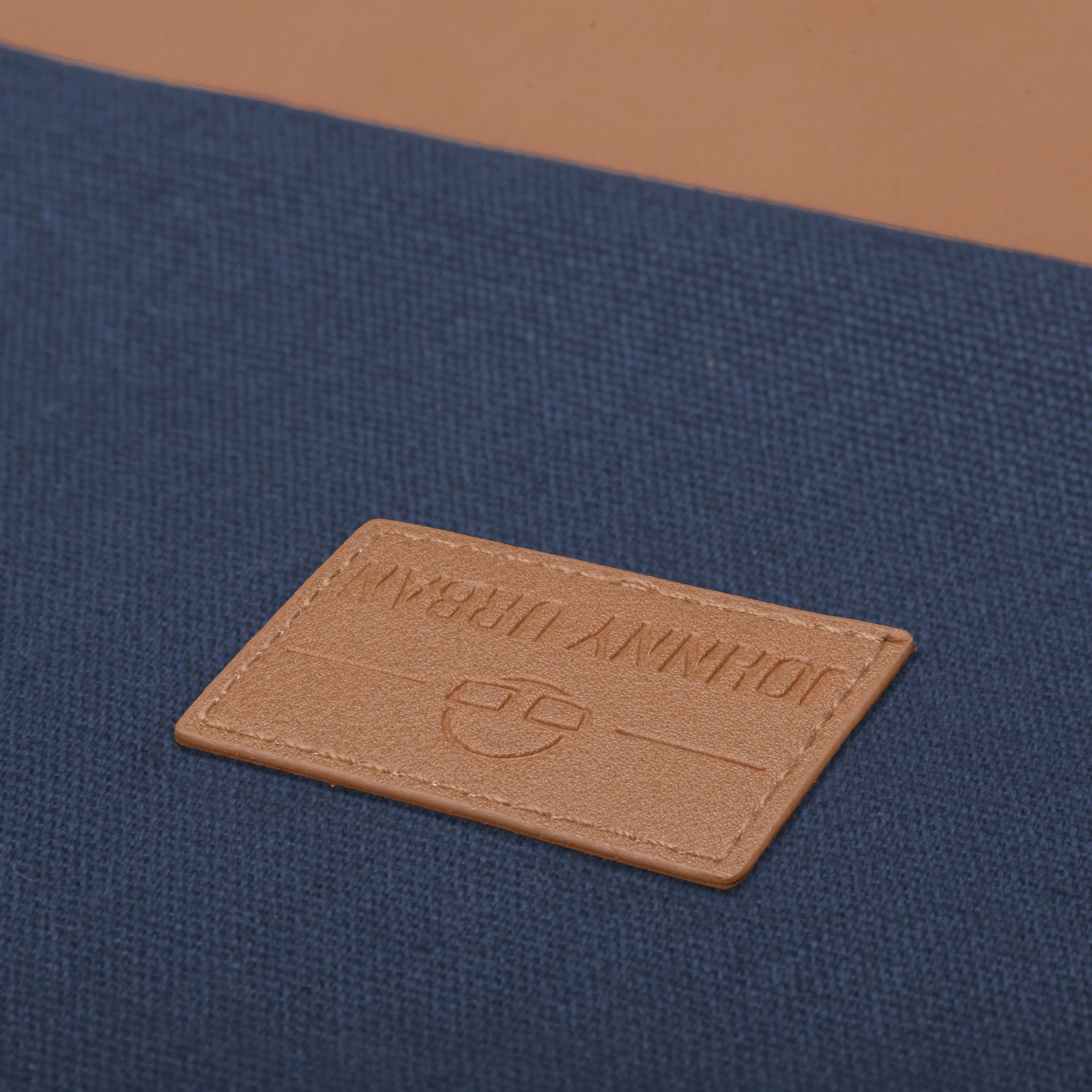 Blaues Gewebe mit braunem, rechteckigem Lederetikett 'Johnny Urban' mit Logo