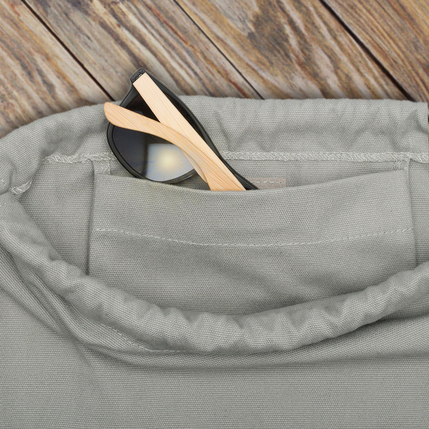 Grauer Turnbeutel 'Luke' aus robustem Stoff mit schwarzer Sonnenbrille, Holzbügel stecken in einer Innentasche