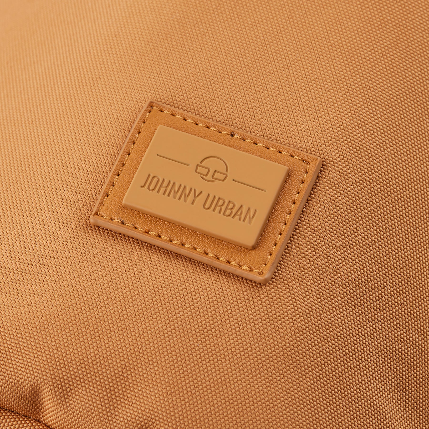 Nahaufnahme des Johnny Urban Logos auf einer karamellfarbenen Umhängetasche