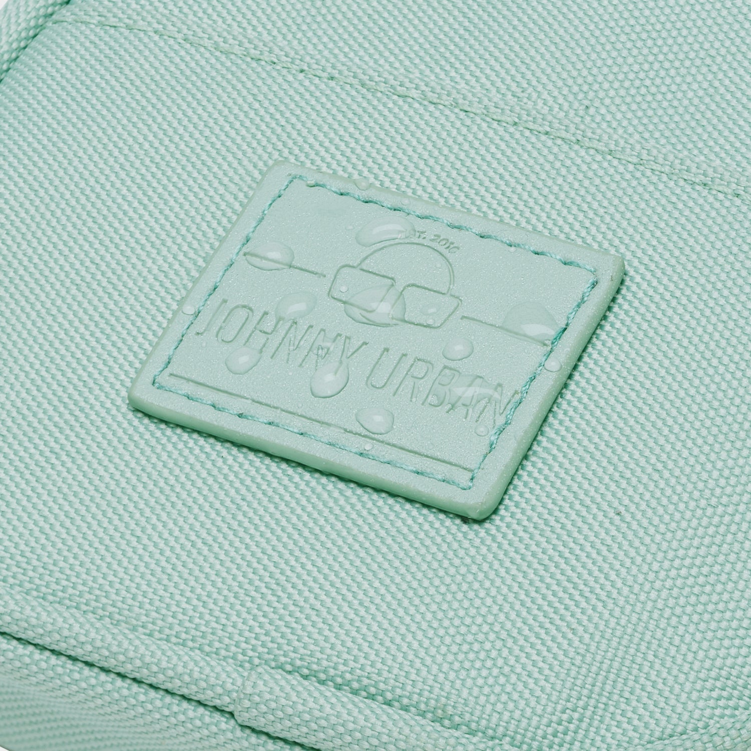 Wasserfester mintfarbener Stoff der Umhängetasche 'Josh' mit Johnny Urban Logo-Patch und Wassertröpfchen