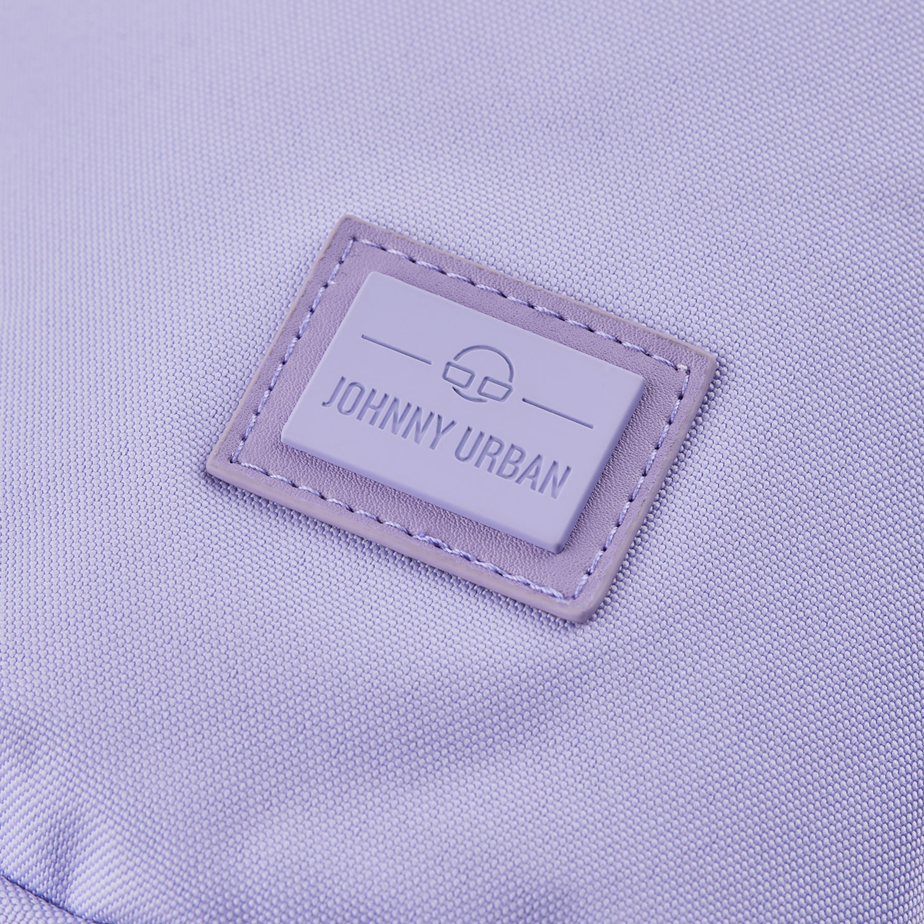 Nahaufnahme des Johnny Urban Logos auf violettem nachhaltigem Stoff der Umhängetasche 'Rue'