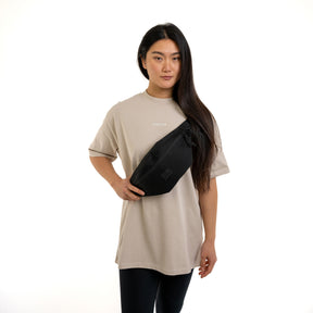 Frau trägt große schwarze Johnny Urban Bauchtasche 'Erik Large' quer über der Brust mit beige T-Shirt