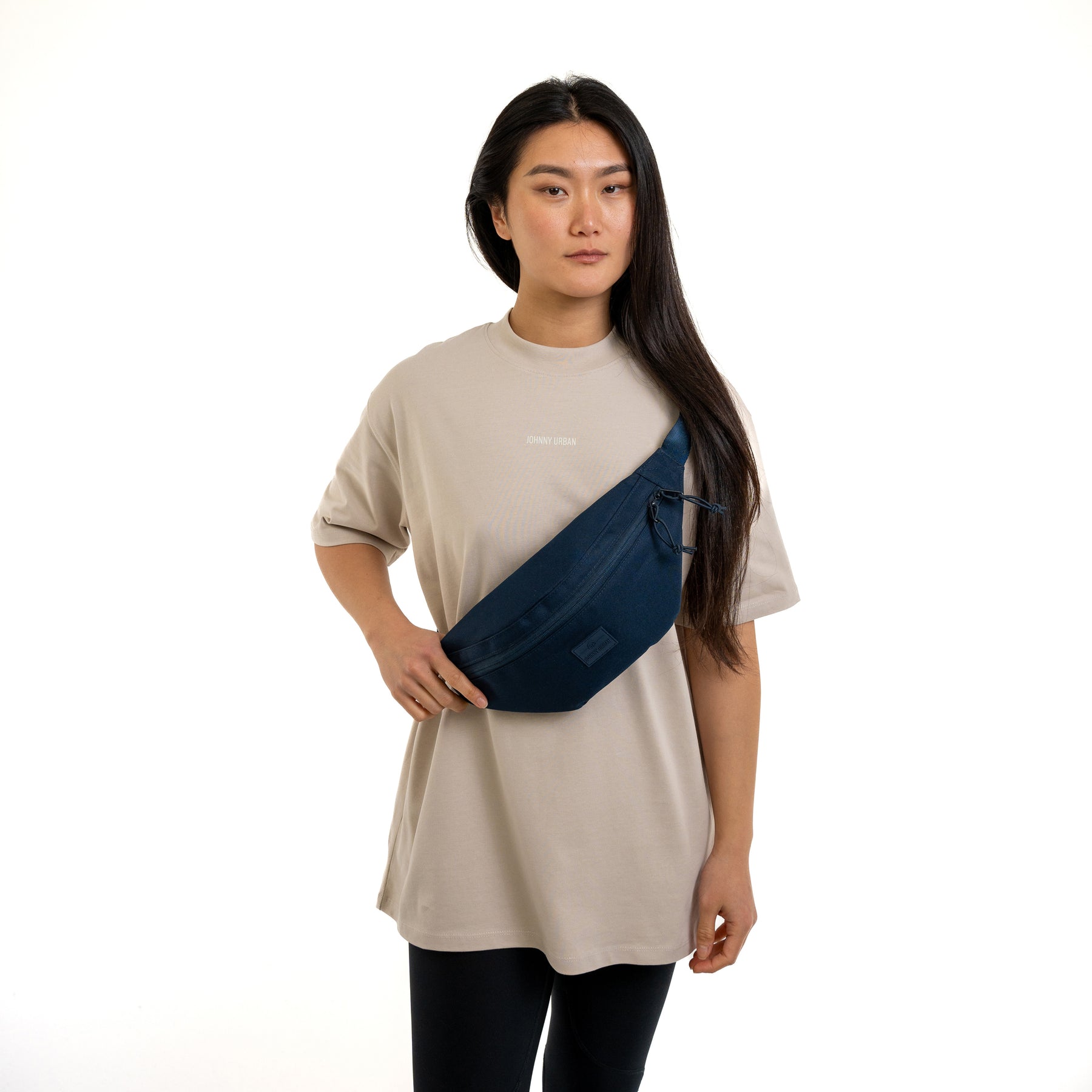 Frau trägt blaue Johnny Urban Bauchtasche 'Erik Large' quer über dem beigen T-Shirt