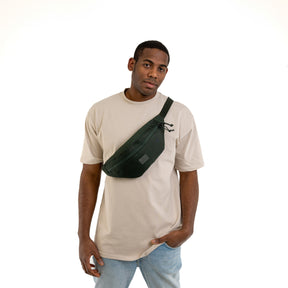 Mann trägt dunkelgrüne Johnny Urban Bauchtasche 'Erik Large' quer über die Brust mit beige T-Shirt und Jeans