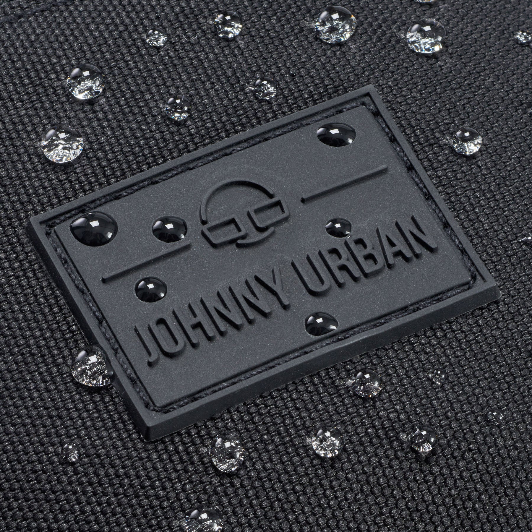 Nahaufnahme der wasserdichten schwarzen Bauchtasche 'Erik Large' von Johnny Urban mit Wasserperlen auf der Oberfläche