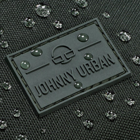 Gummilogo mit Schriftzug 'Johnny Urban' auf wasserabweisendem dunkelgrünem Stoff mit Wassertropfen