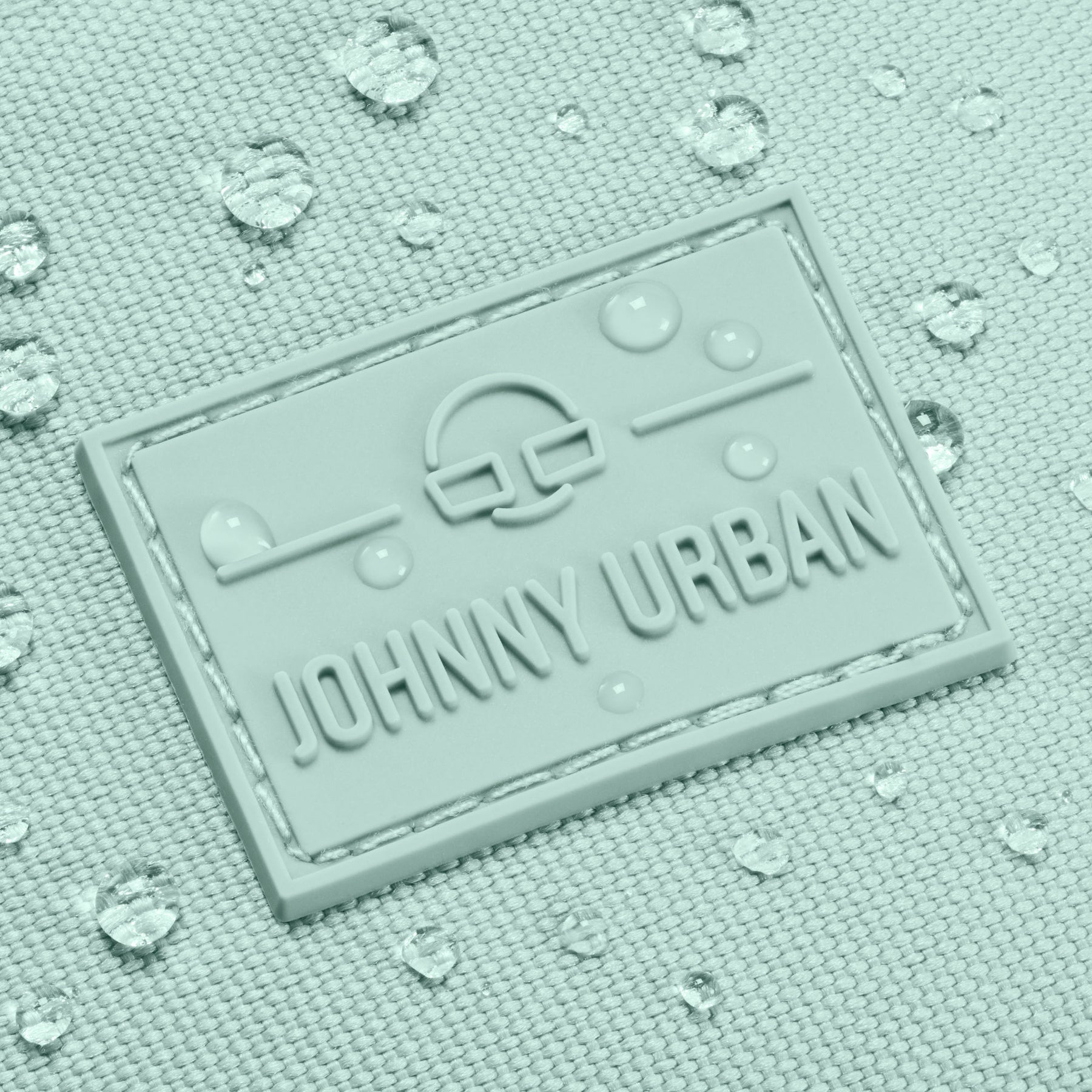 Nahaufnahme des wasserabweisenden Johnny Urban Logos auf der mintfarbenen Bauchtasche 'Erik Large' mit Wassertropfen