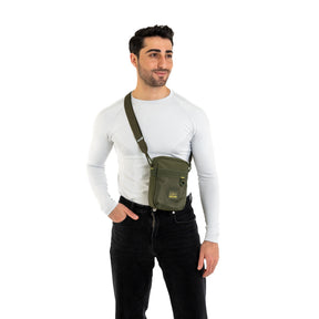Mann trägt olivgrüne Johnny Urban Umhängetasche 'Jayden' über weißem Langarmshirt und schwarzer Hose