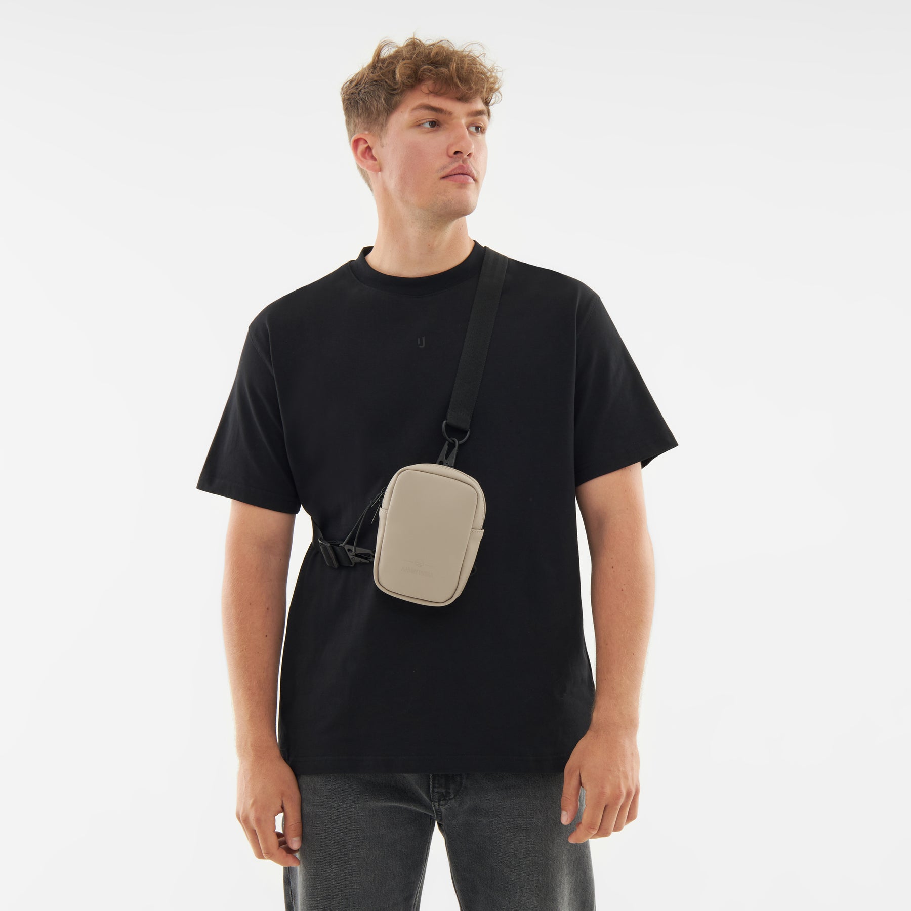 Mann trägt Front Pack "Toby" in Beige quer über schwarzen T-Shirt und Jeans