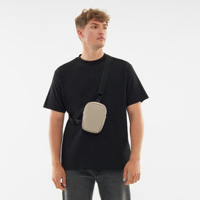 Mann trägt Front Pack "Toby" in Beige quer über schwarzen T-Shirt und Jeans