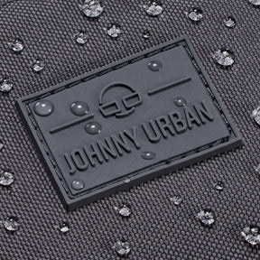 Nahe Aufnahme des wasserdichten, dunkelgrauen Materials der Bauchtasche 'Erik Large' von Johnny Urban mit Logo und Wassertropfen