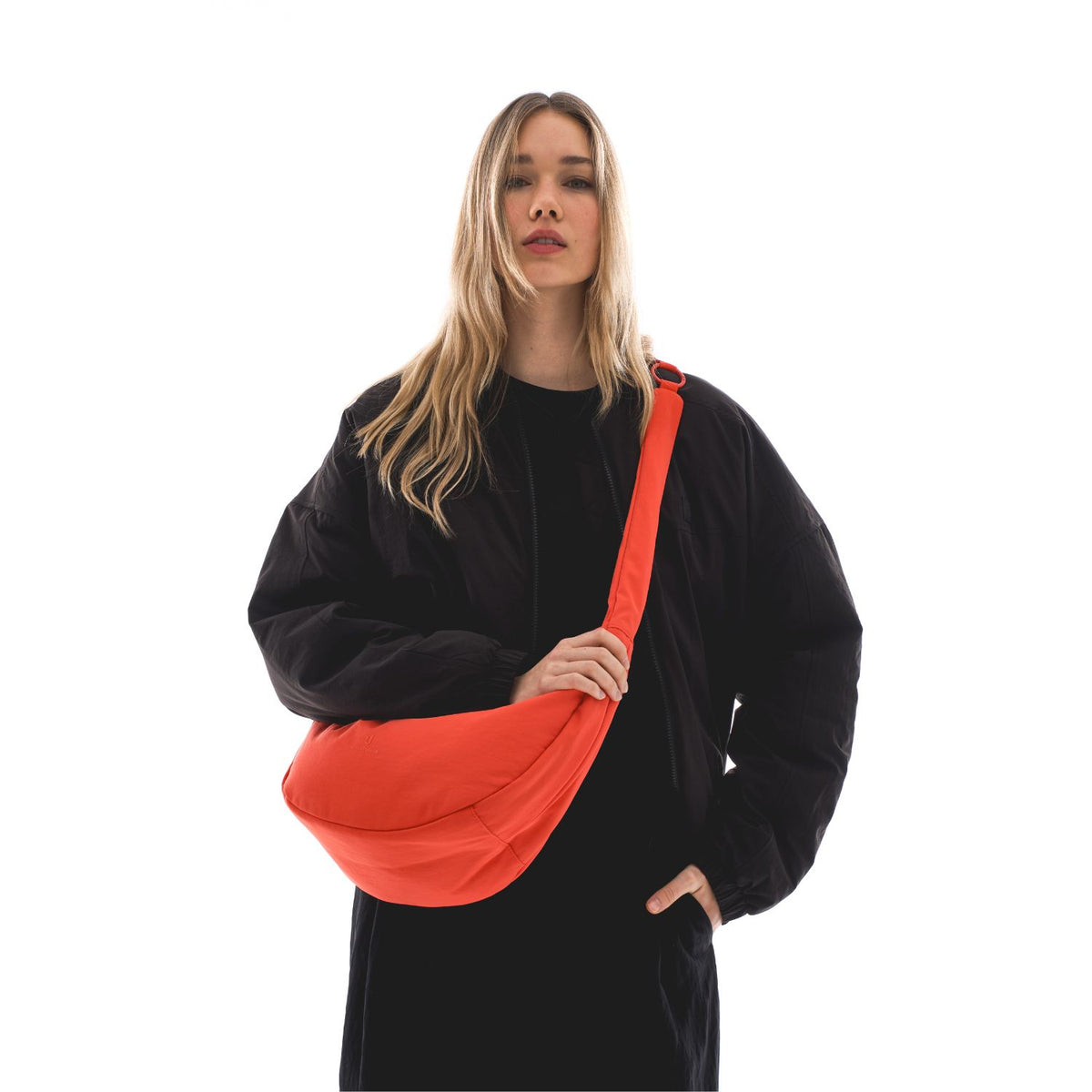 Unser weibliches Model präsentiert sich hier mit der Half-Moon-Bag "Lou Large" in coral-rot. 
