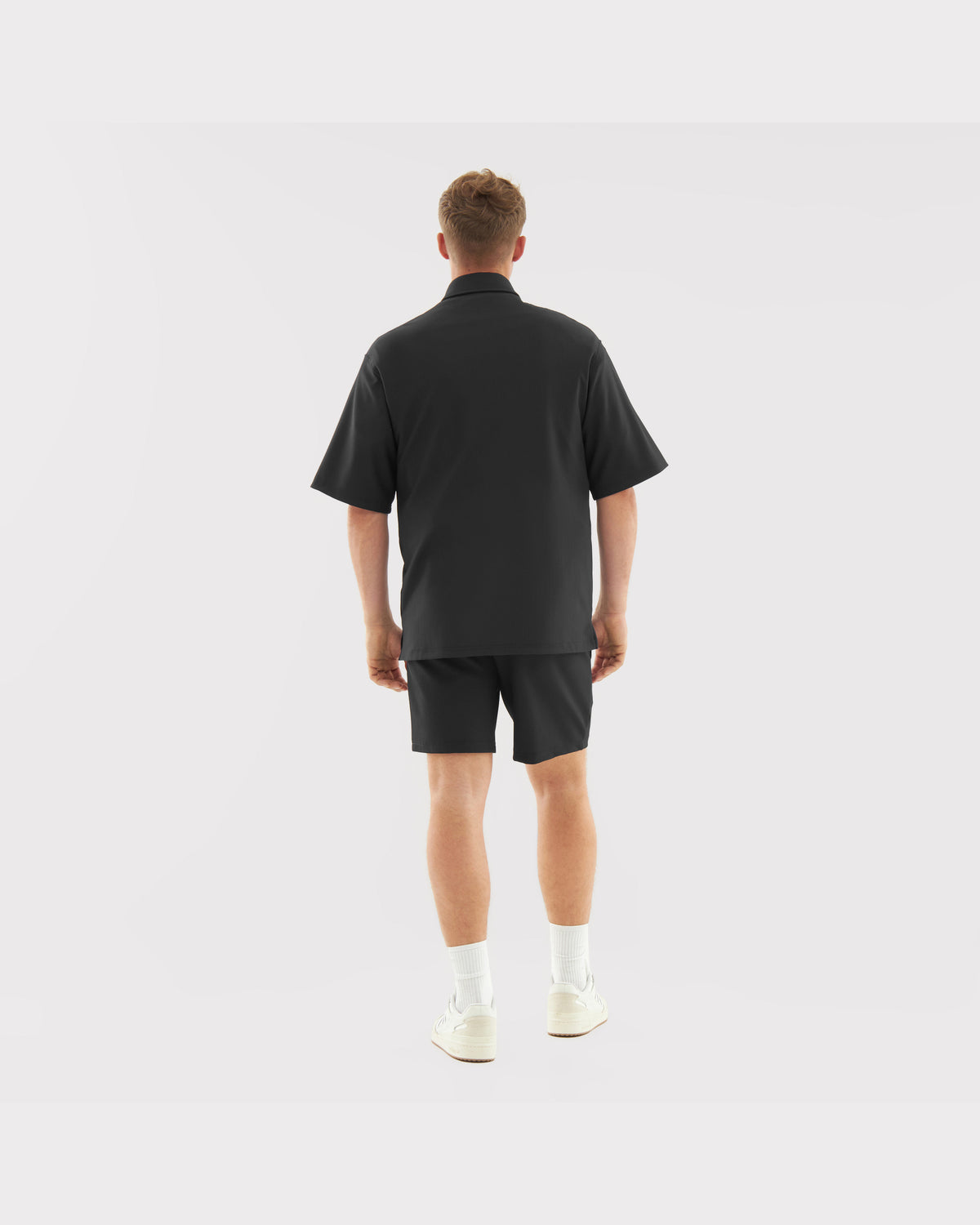 Mann trägt schwarze lockere Herren-Shorts 'Mason' und schwarzes Kurzarmhemd von hinten