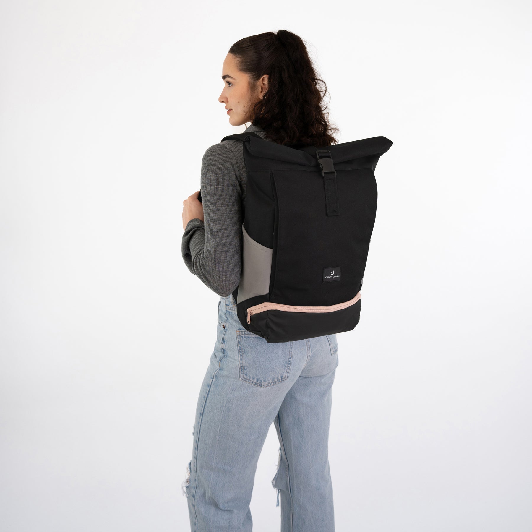 Frau von hinten mit einem schwarzen Rolltop-Rucksack 'Allen Medium' von Johnny Urban und blauer Jeans