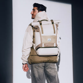 Mann trägt beigen Rolltop Rucksack 'Ashton' von Johnny Urban, dazu beige Jacke und graue Jeans
