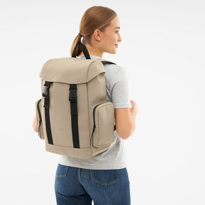 Beige Rucksack 'Finley' mit schwarzen Verschlüssen, getragen von Frau in grauem T-Shirt und blauer Jeans