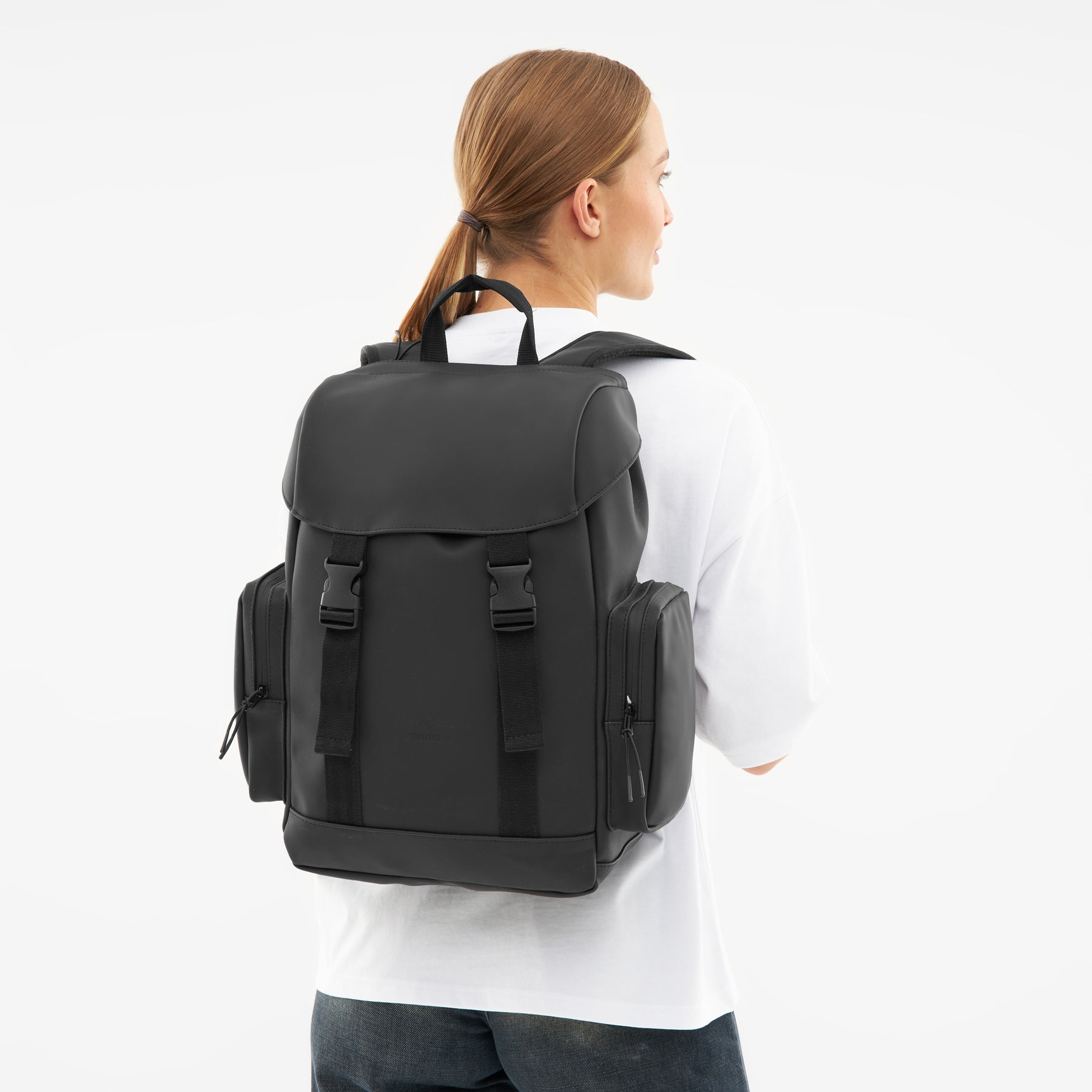 Schwarzer Rucksack 'Finley' mit seitlichen Reißverschlusstaschen, getragen von Frau mit weißem Shirt und Zopf