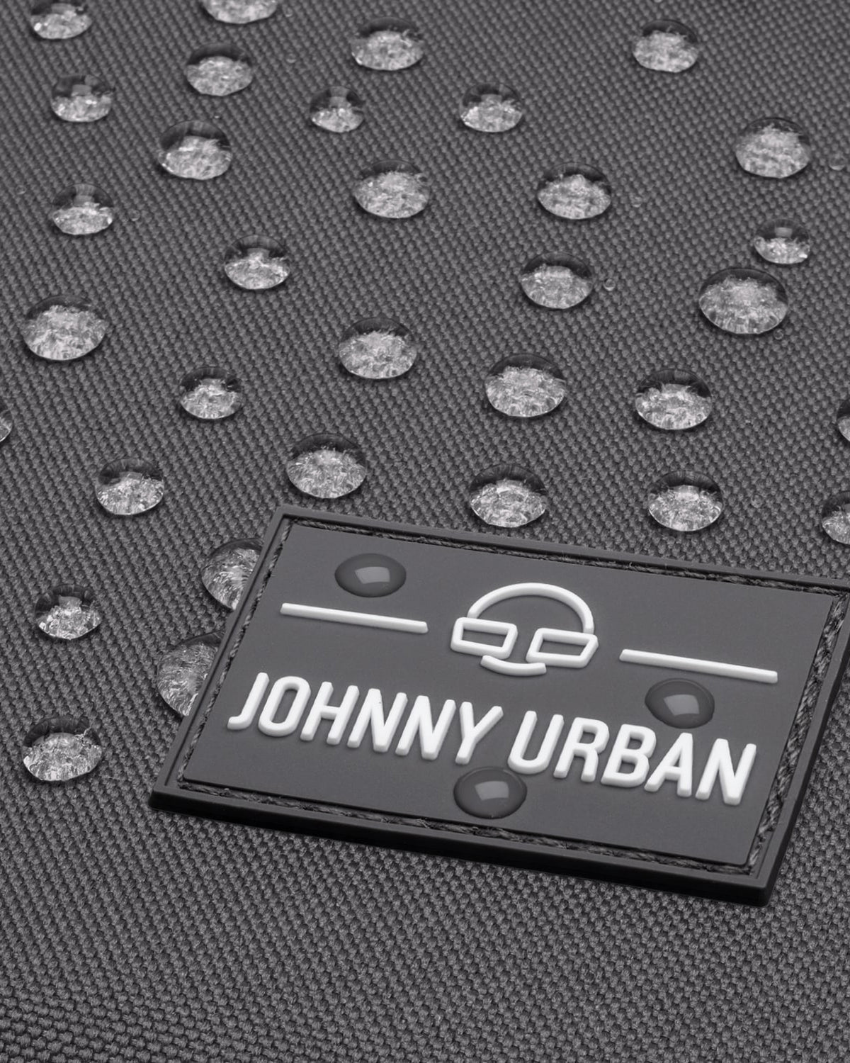 Wasserdichte Oberfläche mit Wassertropfen auf Johnny Urban Logo am Rolltop Rucksack 'Robin Medium'
