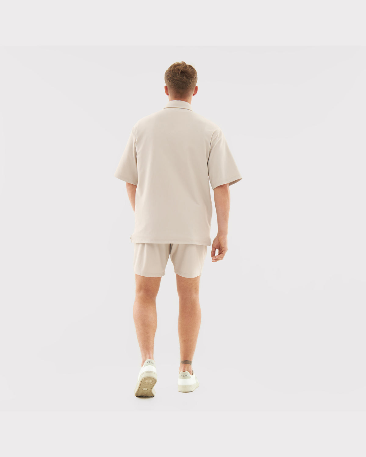 Mann trägt sandfarbenes Sommeroutfit von Set 'Mason' mit lockerem Hemd und Shorts