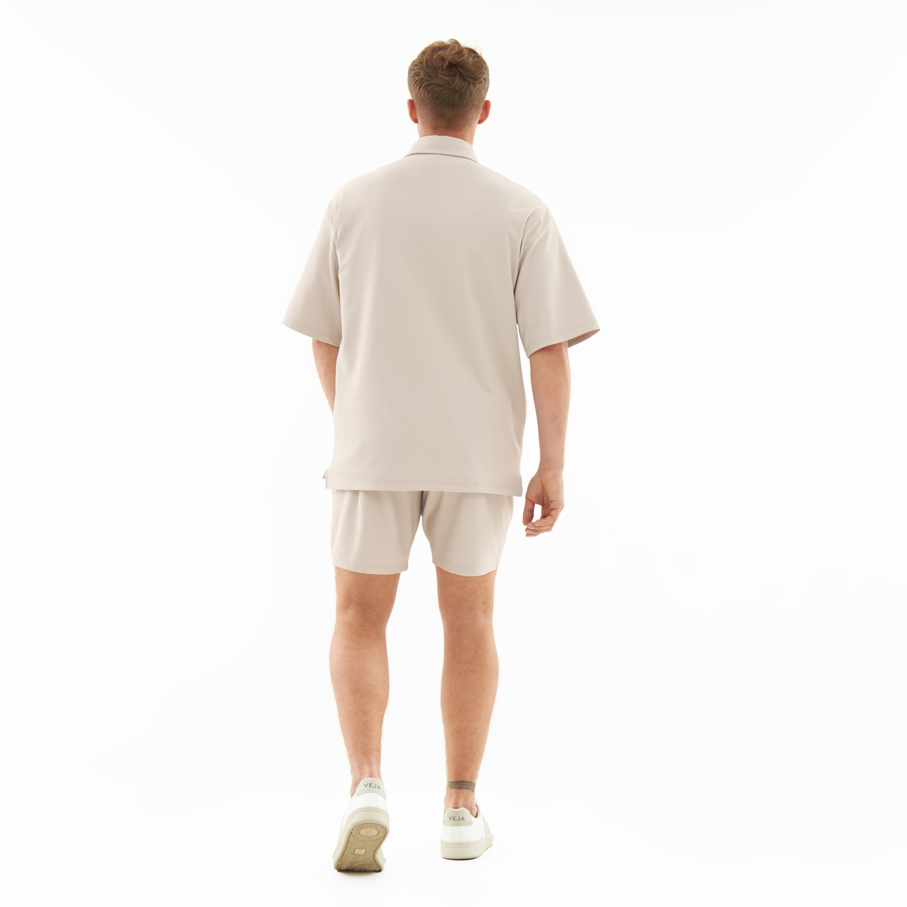 Mann trägt sandfarbenes Sommeroutfit von Set 'Mason' mit lockerem Hemd und Shorts
