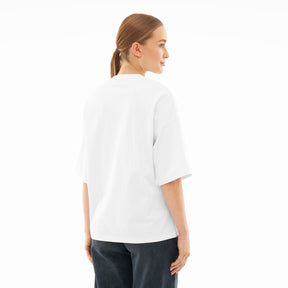 Frau trägt weißes Oversize-T-Shirt 'Vic' von hinten mit dunkler Hose