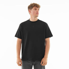 Mann trägt schwarzes Oversize-T-Shirt 'Sammy Butterfly' mit kleinem Logo vorn