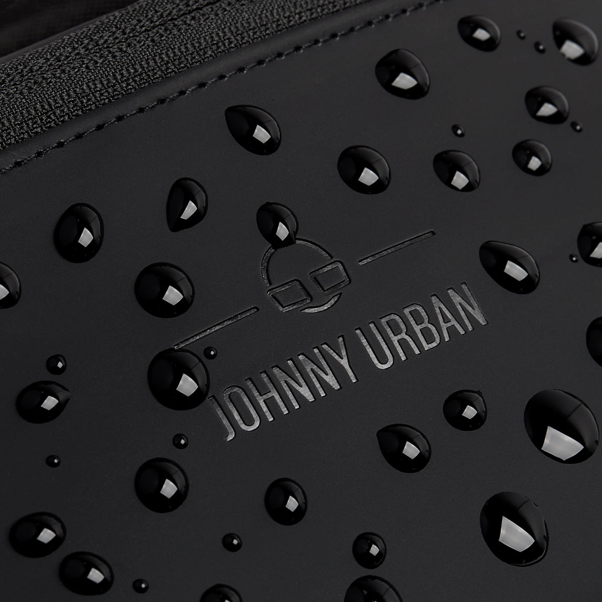 Nahaufnahme der wasserabweisenden Oberfläche der schwarzen Johnny Urban Bauchtasche 'Riley' mit Wassertröpfchen
