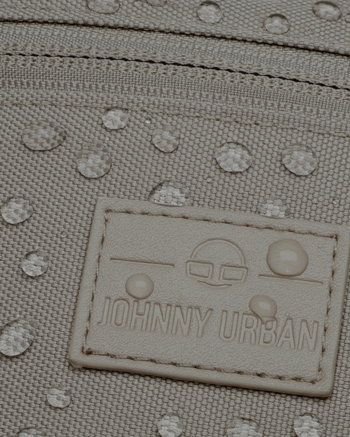Nahaufnahme der wasserabweisenden Oberfläche und des Johnny Urban Logos auf der Bauchtasche 'Erik Small' in desert grey