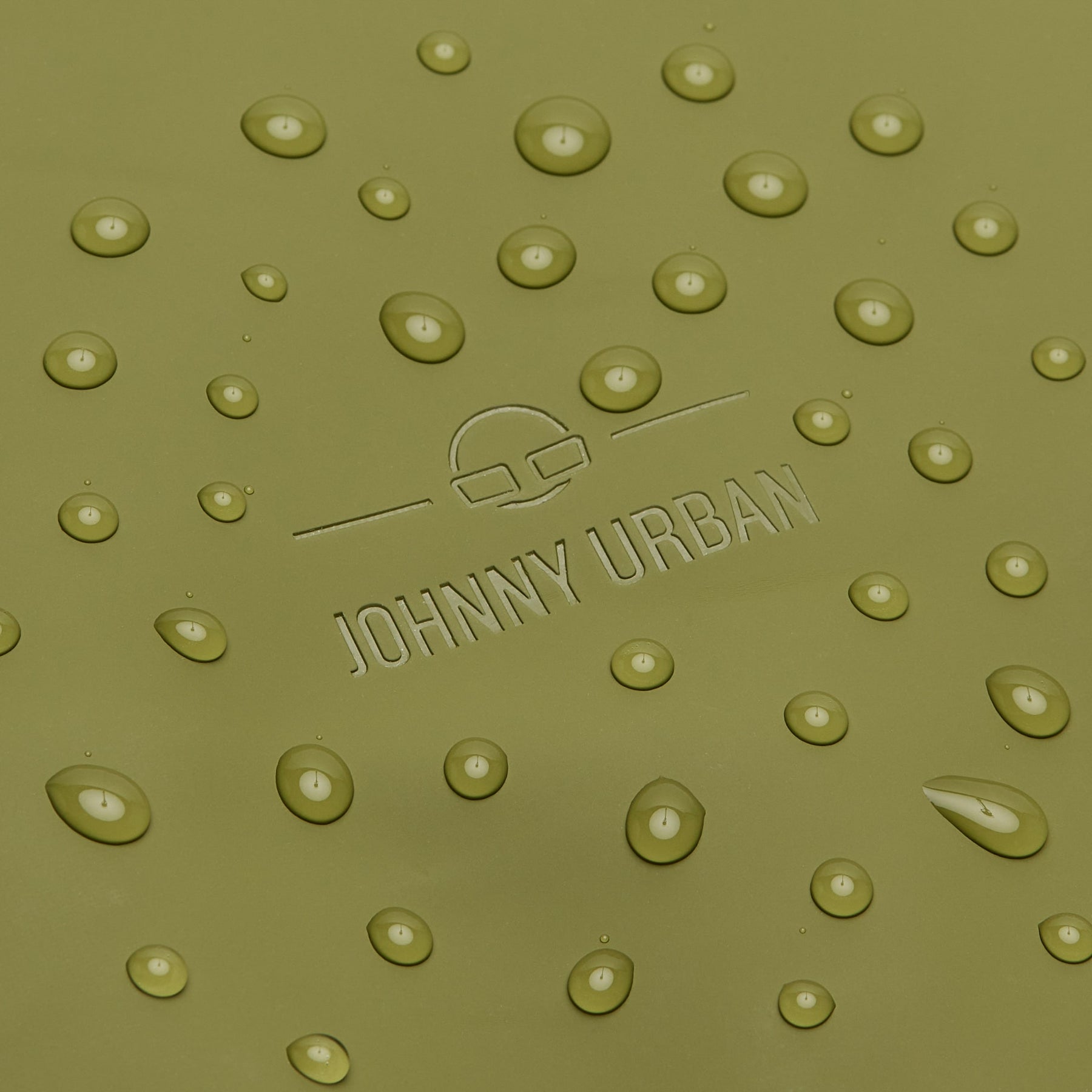 Nahe Aufnahme der wasserabweisenden Oberfläche des olivgrünen Rolltop Rucksacks 'Henry' mit eingelassenem Johnny Urban Logo und Wassertropfen