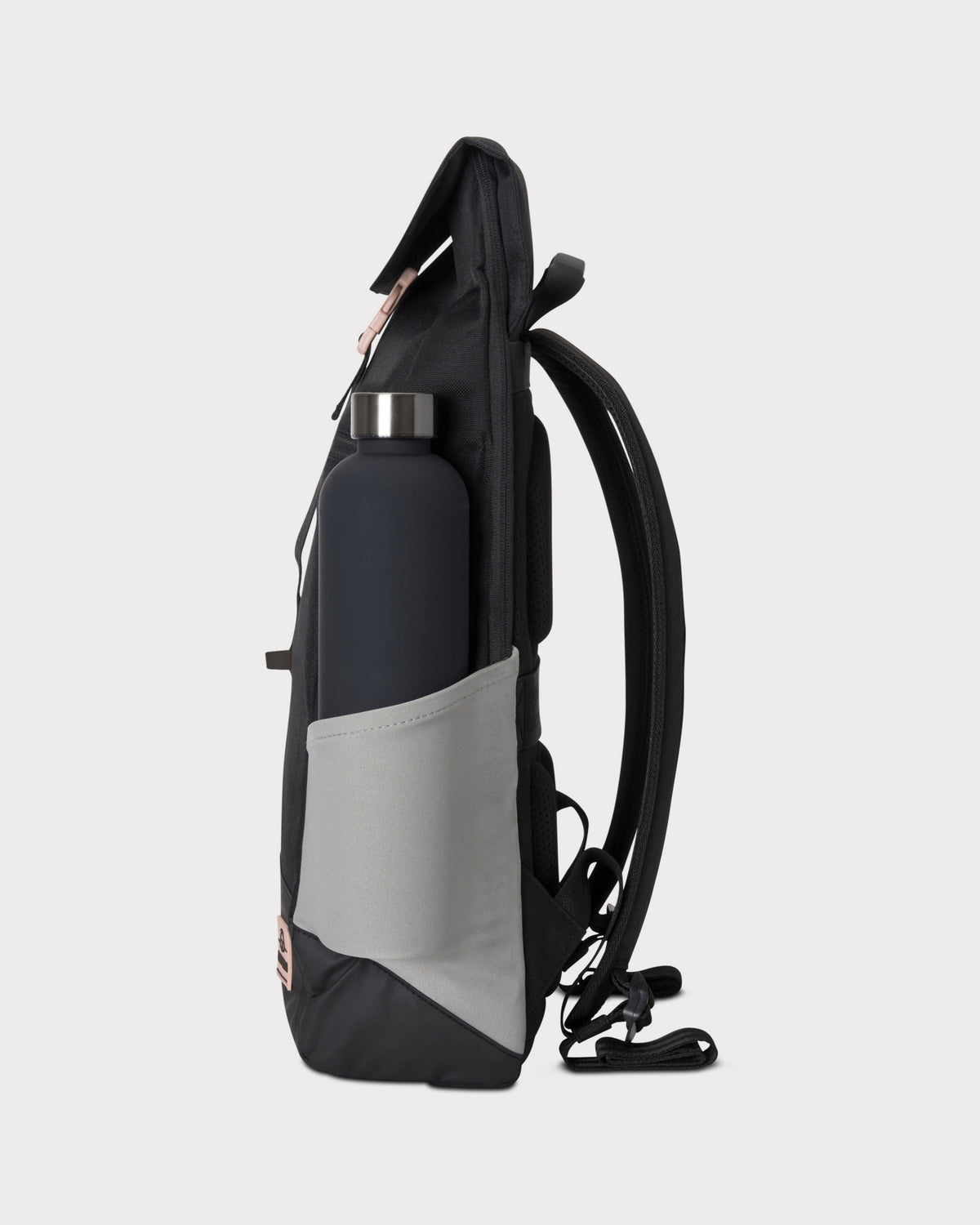 Seitenansicht des schwarzen Rucksacks 'Mika' mit rosa Details und grauer Außentasche mit dunkler Trinkflasche