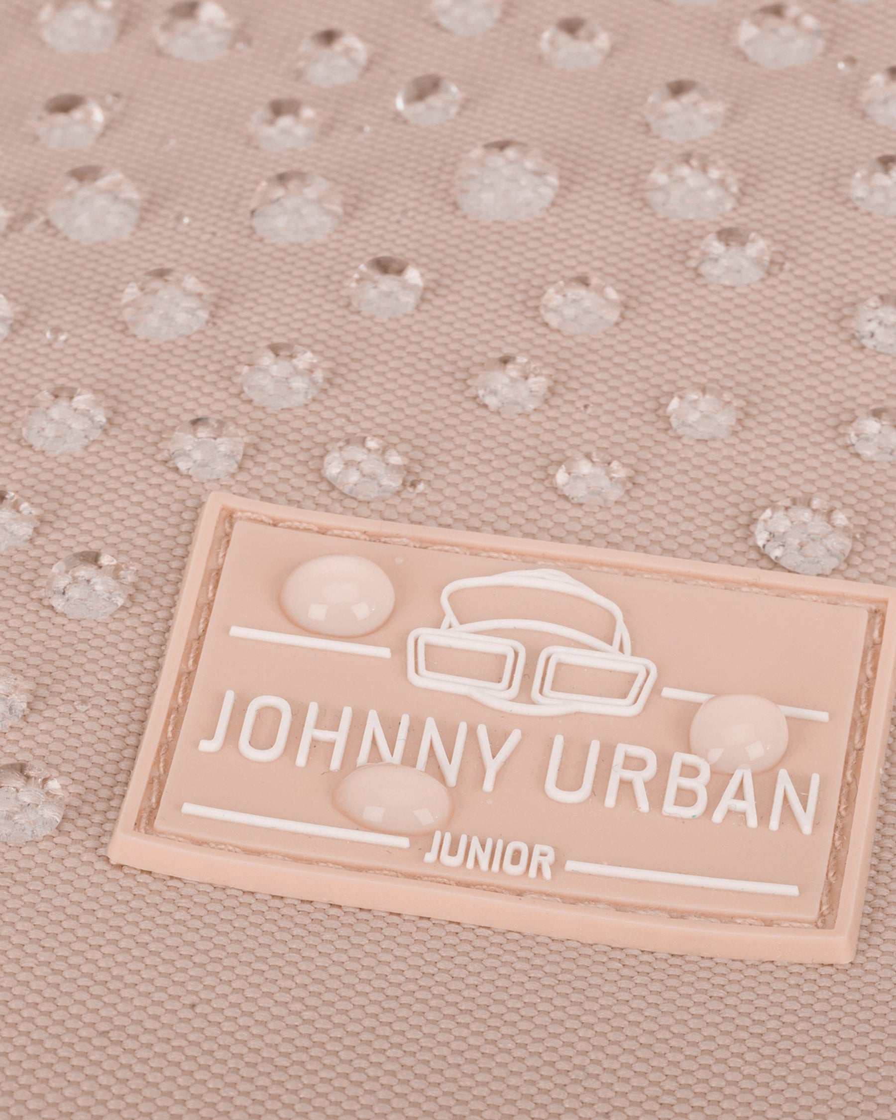 Nahaufnahme des rosa Johnny Urban Junior Labels mit Wassertröpfchen auf wasserdichtem Material
