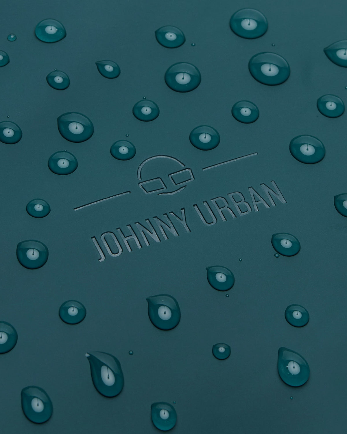 Nahaufnahme des petrolfarbenen Johnny Urban Rolltop Rucksacks 'Henry' mit Wasserperlen auf der Oberfläche